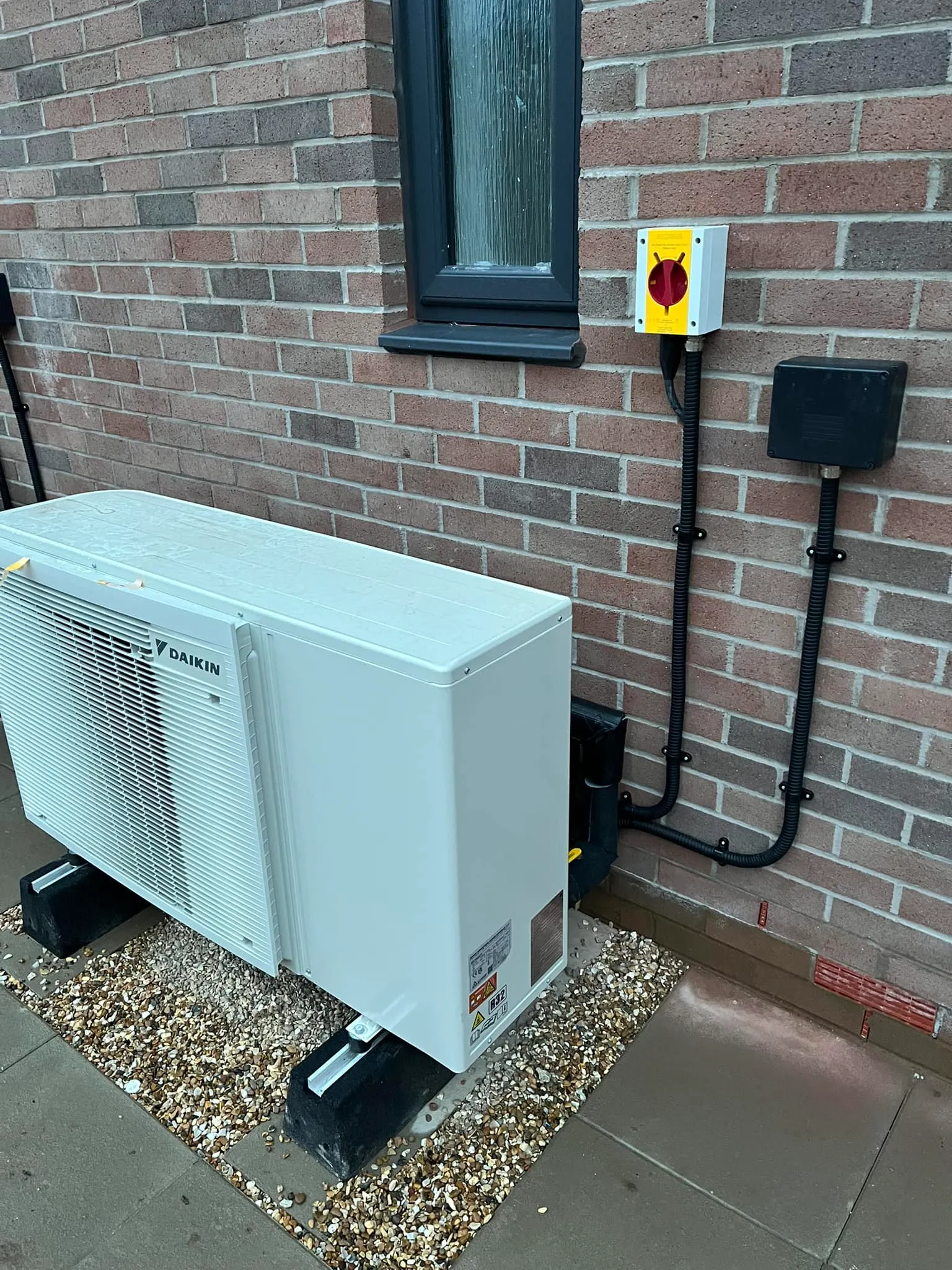 A white air conditioner sitting in front of a brick building.