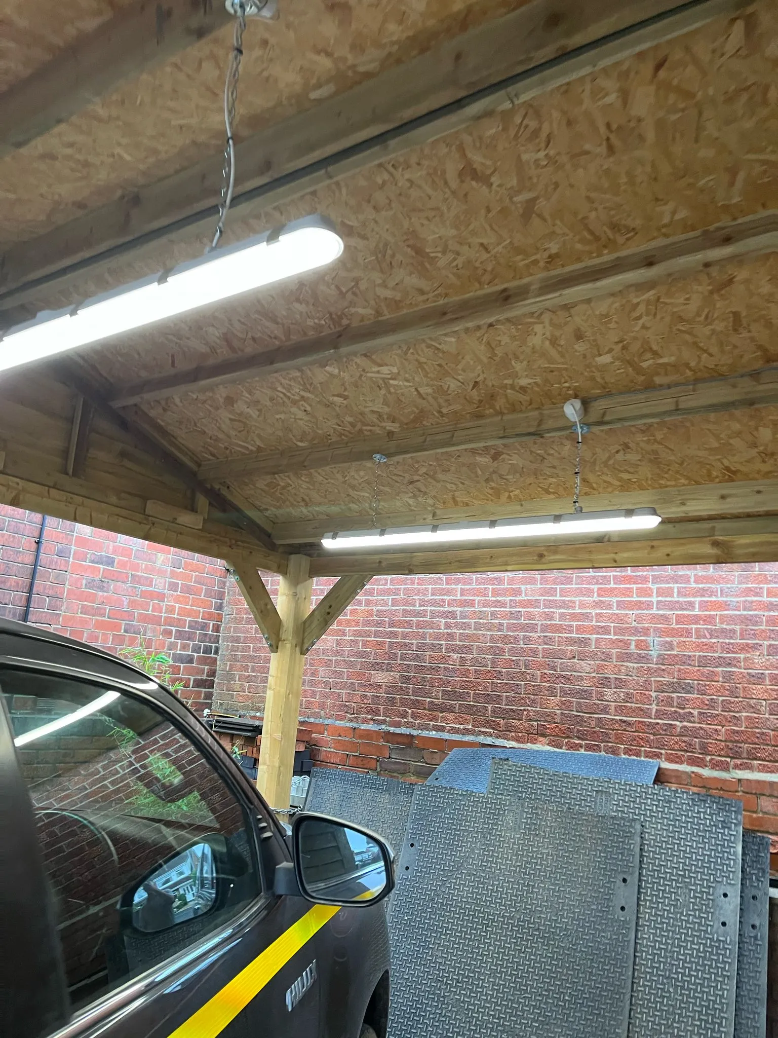 A car is parked under a wooden structure.